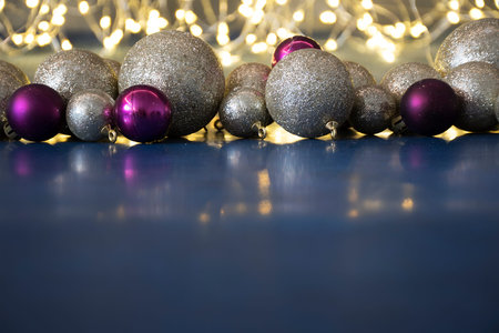 Colorful and shiny Christmas tree baubles on dark blue surface. Copy space for text. Shiny lights on...