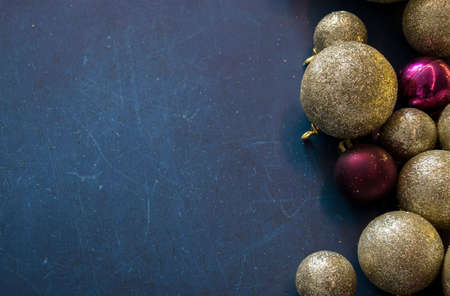Golden and pink shiny Christmas tree baubles on dark blue retro background. Colorful and festive decorations. Selective focus on the balls, blurred background.の写真素材