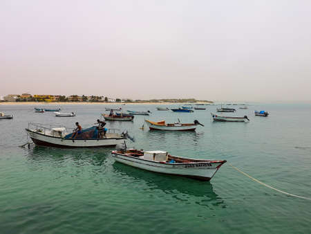 Sal Rei, Cape Verde - February 10th 2019: fishing boats in the ocean and local kids catching the fish to sell.のeditorial素材