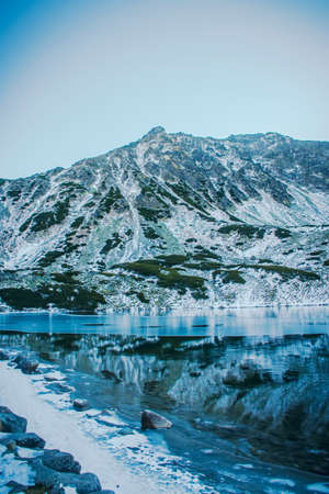 Freezing lake in Dolina PiÄciu StawÃ³w, Tatra National Park, Poland. Early morning in the valley. Selective focus on the rocks, blurred background.の写真素材