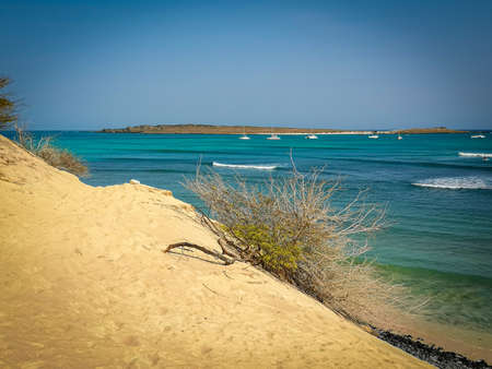 Wavy Atlantic Ocean in Cape Verde. Tropical view from a majestic sand dune. Boats are floating in the marine. Selective focus on the horizon, blurred background.の写真素材
