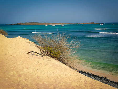 Sunny day on African Island, Cape Verde. Seascape view from a large sand dune. Black pebbles on the shore. Selective focus on the horizon, blurred background.の写真素材