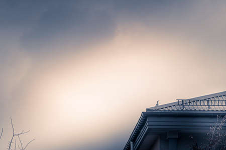 Dramatic sky and a part of building in a city. Colorful bright cloudscape, urban autumn view in Warsaw, Poland. Selective focus on the exterior, blurred background.の写真素材