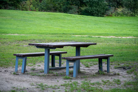 Outdoor table and benches in a park, Vilnius, Lithuania. Picnic space in the city. Green lawn, warm summer day. Selective focus on the furniture, blurred background.の写真素材