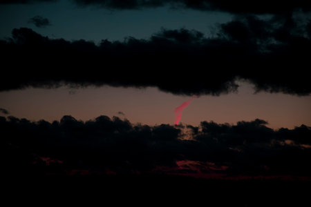 Dark romantic evening sky. Black fluffy clouds, soft pastel colors, unsymmetrical silthouette and...