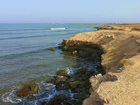 Atlantic Ocean coastline in Cape Verde. Steep rocks on the shore, calm water, clear blue sky and tropical climate. Selective focus on the surface, blurred background.の写真素材