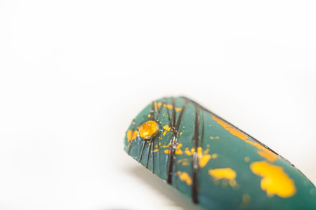Green nail tip with golden elements. Decorative beauty salon design example on a plastic fingertip....
