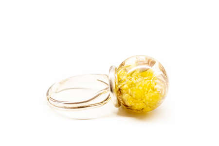Sphere ball made of epoxy resin with yellow immortelle flowers inside. Silver colored metal ring base. Selective focus on the details, object isolated on white background.の写真素材
