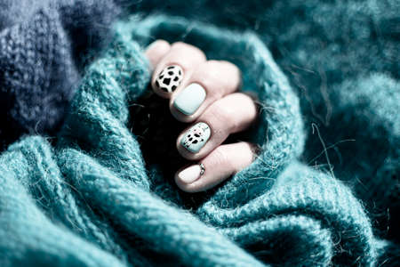 Adorable nails closeup with painted cow. Funny and creative design for summer. Neat manicure in a salon. Selective focus on the details, blurred background.の写真素材