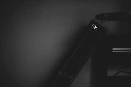 Creative dark guitar case closeup. Grey wall, leather container for a musical instrument, underexposed shot. Selective focus on the details, blurred background.の写真素材