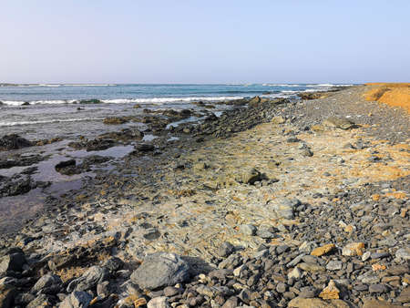Sandy valley in a rocky terrain. Bright desert view, low volcanic hills, clear blue sky in Cape Verde. Selective focus on the details, blurred background.の写真素材