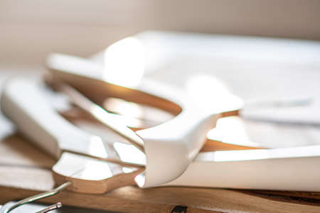 Blurry closeup of a pile of hangers. Materials made of brown natural wood and white plastic. Indoor view. Selective focus on the details, blurred background.の写真素材