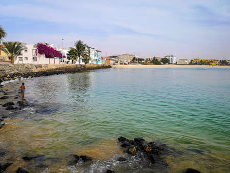 Sal Rei, Cape Verde - February 14th 2019: local kid ready to swim in the lagoon. Romantic coastline view on Boa Vista Island. Small houses on the shore.のeditorial素材