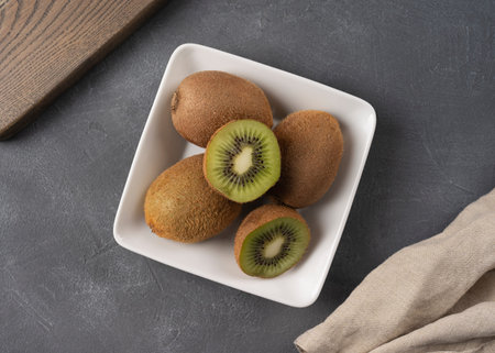Fresh organic kiwi fruit on a plate, on a gray table background. Selective focus. Rustic style....
