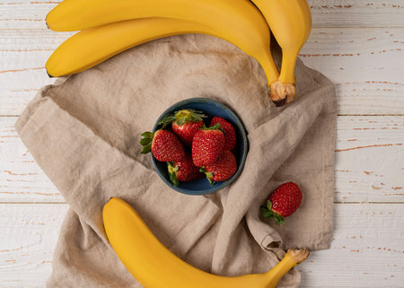 Close up top view of sweet bananas and ripe strawberries on a linen cotton towel, organic healthy food conceptの写真素材