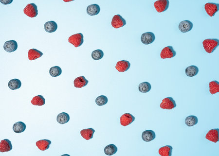 pattern of blueberry and raspberry, top view, flat lay image of berries on a blue background