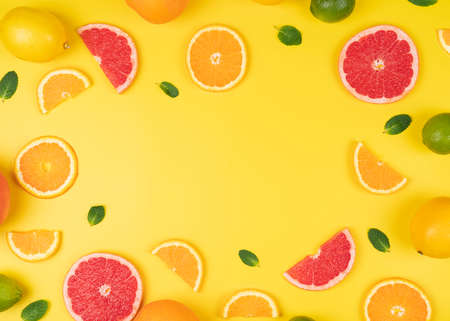 Flat lay composition with slices of fresh orange, grapefruit on yellow background top view copy space. Citrus juice concept, ready to eat. Creative summer backgroundの写真素材