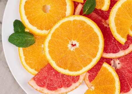 Macro view of sliced juicy oranges and grapefruit with mint leaves, close up view of citrus fruit in high resolution, with visible textureの写真素材