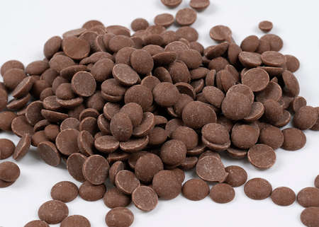 Close up of chocolate drops on a white background. Chocolate pieces for dessert decoration or ready to eat, top viewの写真素材