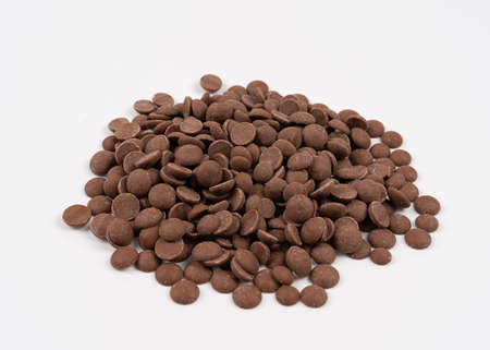Pile of delicious milk chocolate chips on white background. Scattered chocolate drops on white background isolation top viewの写真素材