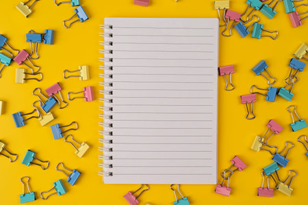 School stationery and blank paper notebook on yellow background with paper clips. ... Back to school...