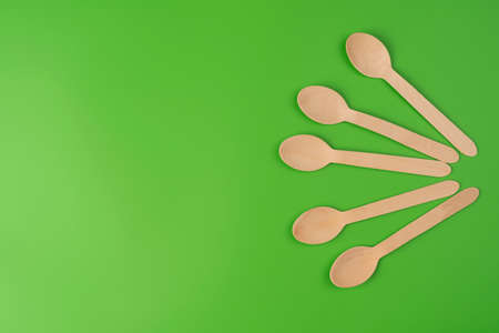 Spoons are arranged in a row. Eco-friendly tableware from green color backgroundの写真素材
