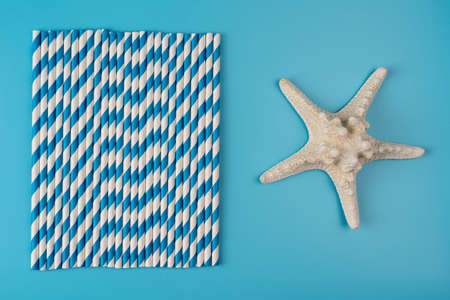 Drinking straws on blue background. Top view of colorful paper disposable eco-friendly straws for summer cocktails. With starfish, vacation eco friendly conceptの写真素材