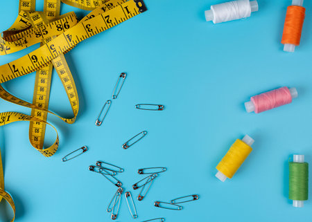 Sewing accessories and fabric on a blue background. Sewing threads, pins, fabric, buttons and sewing...