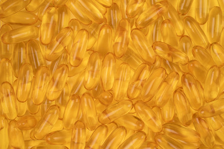 Health supplement fish oil gel capsules background. Bright gold background with oil omega 3, 6...