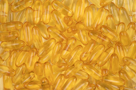 gold cod liver fish oil capsule, vitamin D on background. Clear yellow vitamin capsules for health close upの写真素材