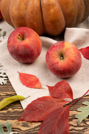 fresh red apples with leaves on wooden table with autumn leaves. organic fresh sweet ripe applesの写真素材