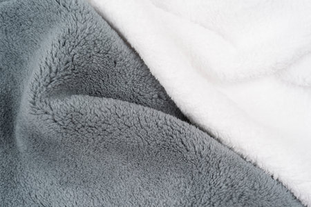 Fleece. Close-up warm, softness gray and white plaid on the bed, top view. Crumpled soft blanket of...