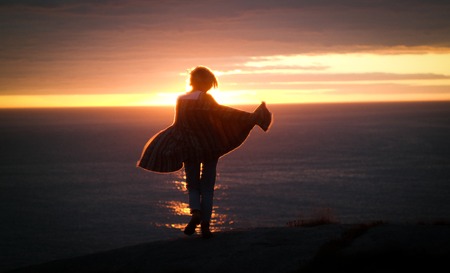 Young woman dancing on the ocean during sunset.の写真素材