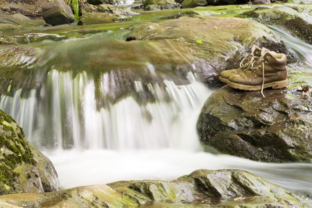 A pair of hiking boots at the waterfall.の写真素材