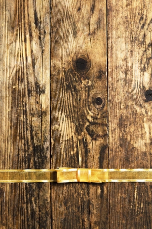 Rustic wooden background with gold ribbon bow の写真素材