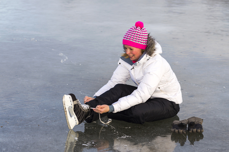 Young girl on ice skates shoes take up.の写真素材