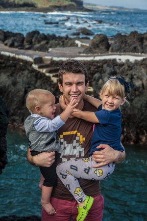 Father and children stay near the sea shore in Garachico, at the north of Tenerife, Spainの写真素材