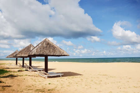 Cane umbrella and deck chairs on the sandy beach near the blue sea - Phu Quoc island in vietnamの写真素材