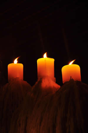 tripple candle showing candlelight in the darkの写真素材