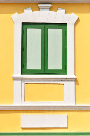 the closed green window on the yellow wallの写真素材