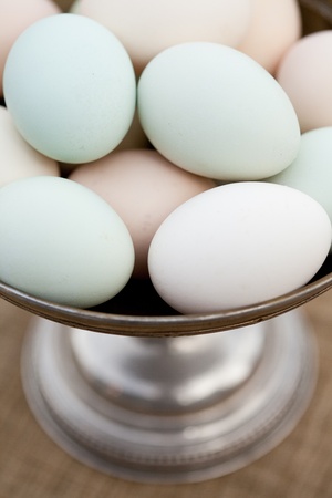 One dozen free range, organic eggs grouped together in a silver bowl.の写真素材