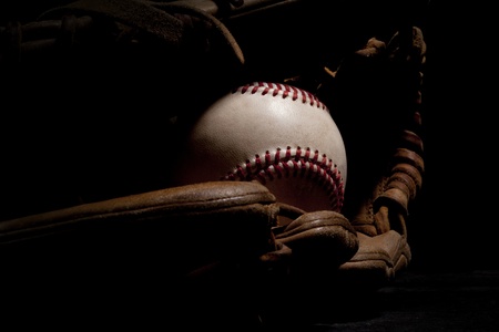 Macro shot of worn baseball and glove isolated on a black background  の写真素材