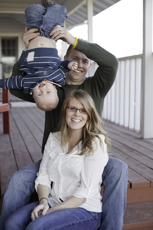 A young mother and father playing with their young son on the back porch の写真素材