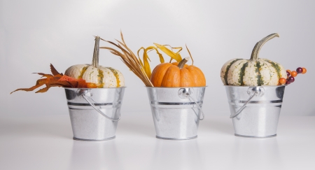 Three metal buckets are filled with fall pumpkins and decorations の写真素材