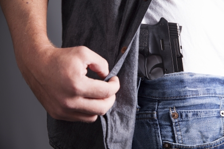 A man reveals a concealed pistol at his side  の写真素材