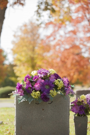 A beautiful spray of purple flowers grace the top of a tombstone in the fall の写真素材