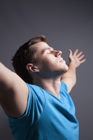 A peaceful man looks upward with outstretched arms の写真素材