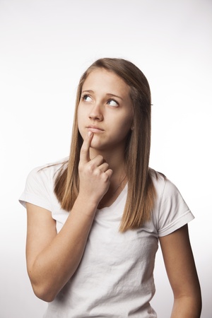 A young female teen wearing white looks off into the distance and thinksの写真素材
