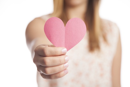 A young woman holds out a cut out construction paper heart の写真素材