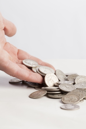 A pile of shiny money is dropping from a hand on a table   の写真素材